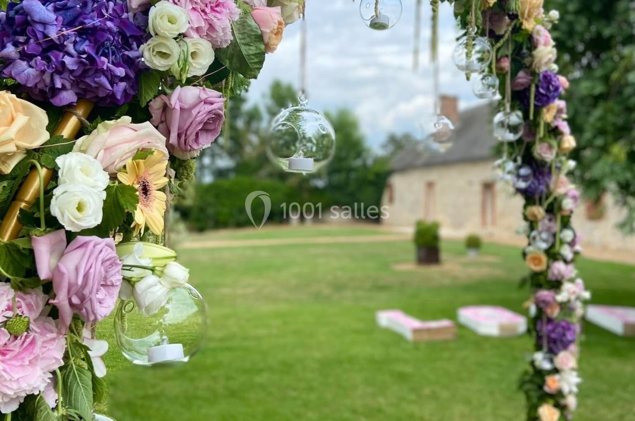 Arche florale ornée de roses, pivoines et hortensias colorés, décorée de boules en verre suspendues, dans un jardin…