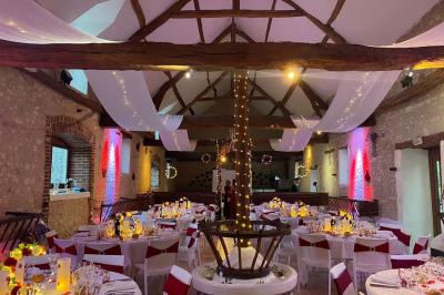 Salle de réception décorée avec des tables dressées, des guirlandes lumineuses et des voilages suspendus au plafond.