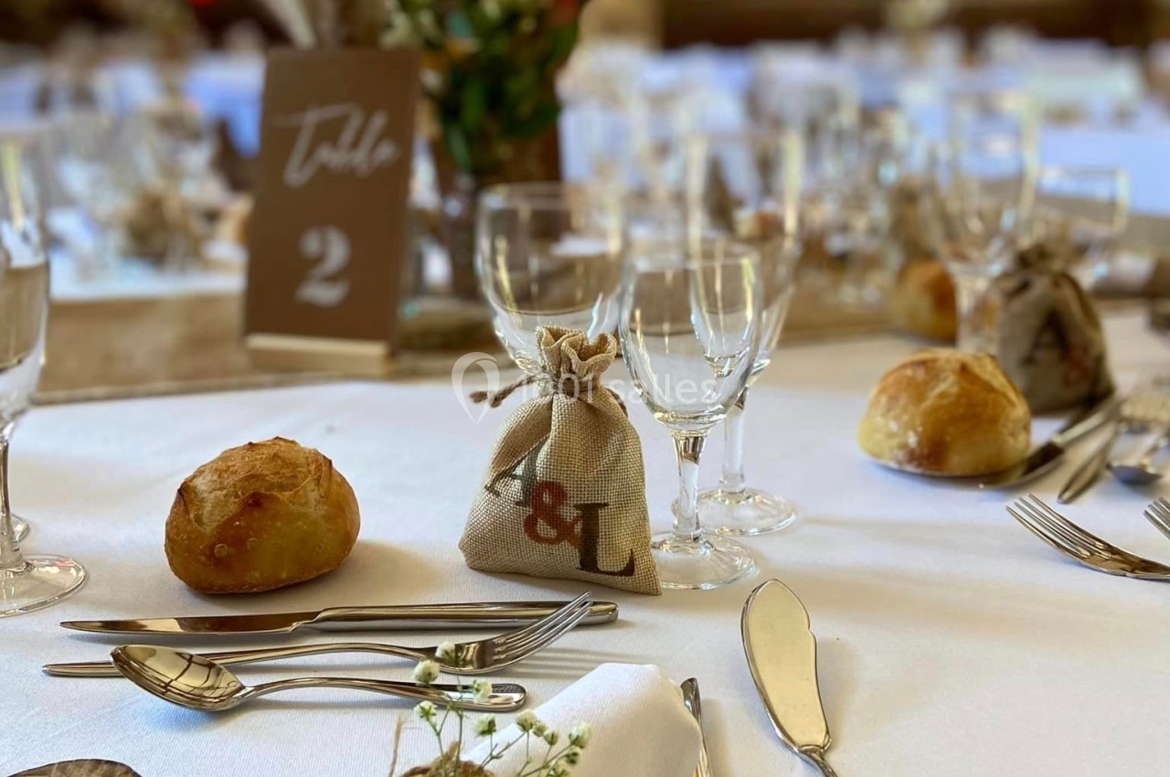 Table de réception décorée avec des éléments rustiques, serviettes enroulées, couverts disposés et petits pains.