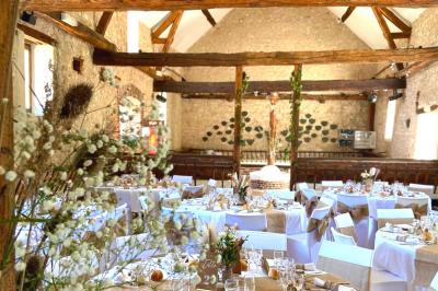 Salle de réception décorée avec des tables dressées, des guirlandes lumineuses et des voilages suspendus au plafond.
