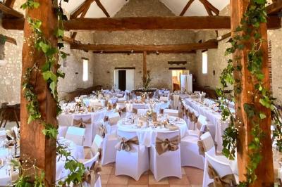 Salle de réception décorée avec des tables dressées, des guirlandes lumineuses et des voilages suspendus au plafond.