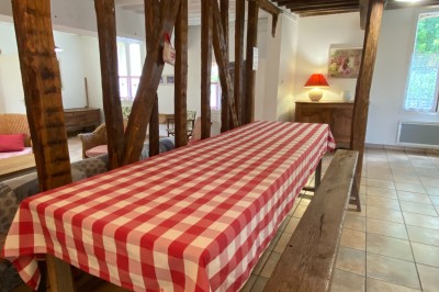 Chambre lumineuse avec poutres apparentes, lit double, miroir doré, chaise en bois et vue sur une fenêtre.
