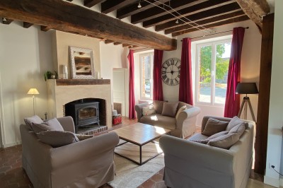 Chambre lumineuse avec poutres apparentes, lit double, miroir doré, chaise en bois et vue sur une fenêtre.