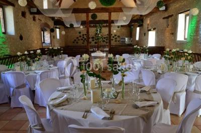 Salle de réception décorée avec des tables dressées, des guirlandes lumineuses et des voilages suspendus au plafond.
