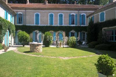 Un homme en costume soulève une femme en robe blanche dans un jardin au coucher du soleil.