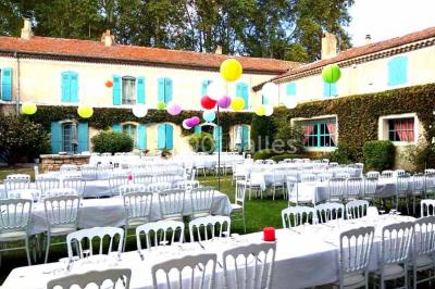 Un homme en costume soulève une femme en robe blanche dans un jardin au coucher du soleil.
