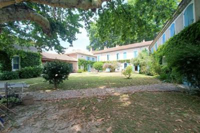 Un homme en costume soulève une femme en robe blanche dans un jardin au coucher du soleil.