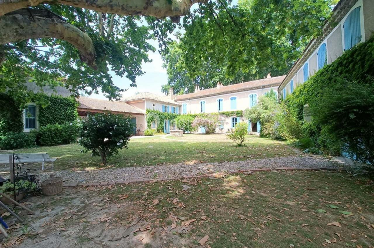 Cour intérieure d'une maison traditionnelle entourée de murs en pierre couverts de végétation et d'arbres.