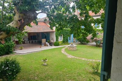 Un homme en costume soulève une femme en robe blanche dans un jardin au coucher du soleil.