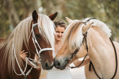 Un homme en costume soulève une femme en robe blanche dans un jardin au coucher du soleil.