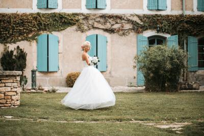 Un homme en costume soulève une femme en robe blanche dans un jardin au coucher du soleil.