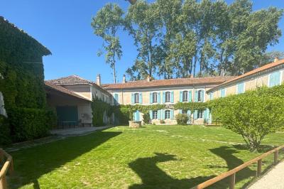 Un homme en costume soulève une femme en robe blanche dans un jardin au coucher du soleil.