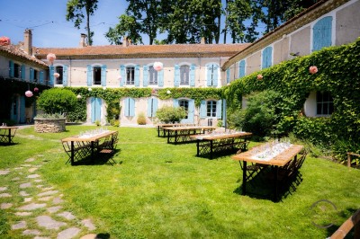 Un homme en costume soulève une femme en robe blanche dans un jardin au coucher du soleil.
