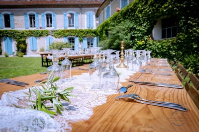Un homme en costume soulève une femme en robe blanche dans un jardin au coucher du soleil.