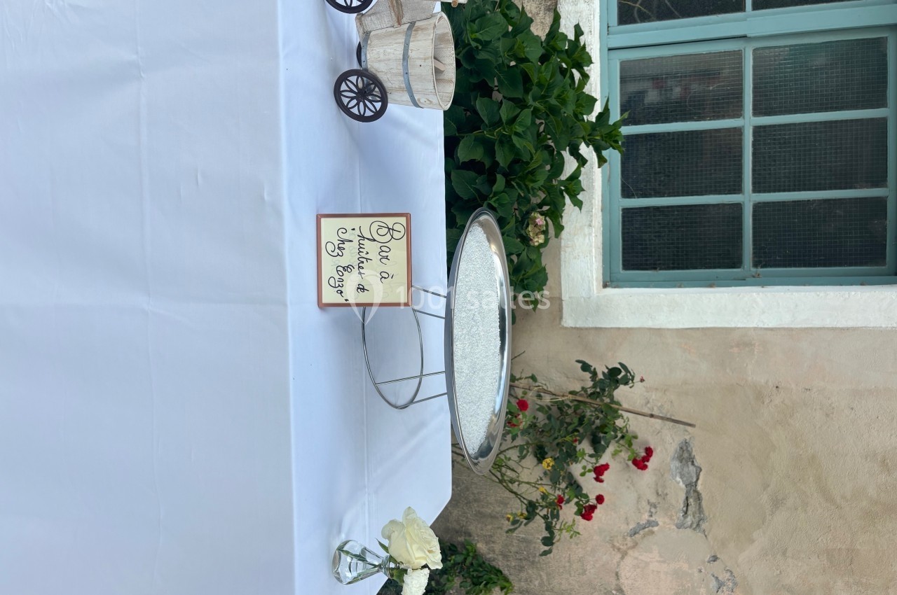 Table décorée avec une nappe blanche, une pancarte ’Bar à limonade’, un vase avec une rose blanche et un petit chariot en…