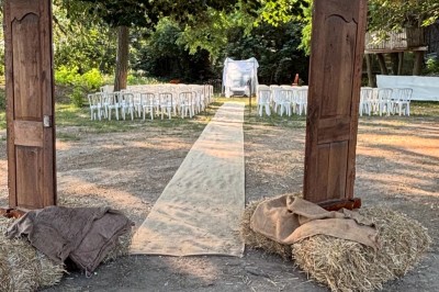Un homme en costume soulève une femme en robe blanche dans un jardin au coucher du soleil.