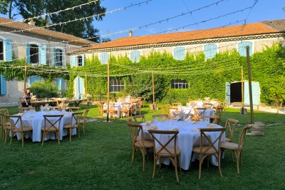 Table en bois à l'extérieur avec des plantes en pot, une boîte aux lettres verte, des paniers et un photomaton en arrière…