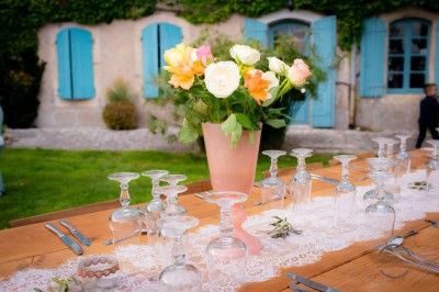 Table en bois à l'extérieur avec des plantes en pot, une boîte aux lettres verte, des paniers et un photomaton en arrière…