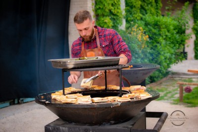 Table en bois à l'extérieur avec des plantes en pot, une boîte aux lettres verte, des paniers et un photomaton en arrière…