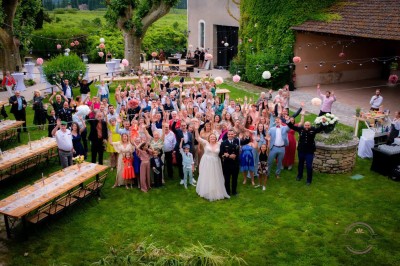 Table en bois à l'extérieur avec des plantes en pot, une boîte aux lettres verte, des paniers et un photomaton en arrière…