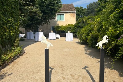 Table en bois à l'extérieur avec des plantes en pot, une boîte aux lettres verte, des paniers et un photomaton en arrière…