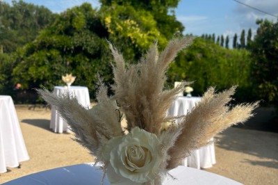 Table en bois à l'extérieur avec des plantes en pot, une boîte aux lettres verte, des paniers et un photomaton en arrière…