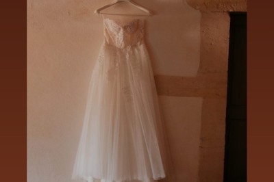 Coccinelle blanche décorée de fleurs blanches pour un mariage, stationnée sous un arbre dans un cadre verdoyant.