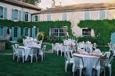 Un homme en costume soulève une femme en robe blanche dans un jardin au coucher du soleil.