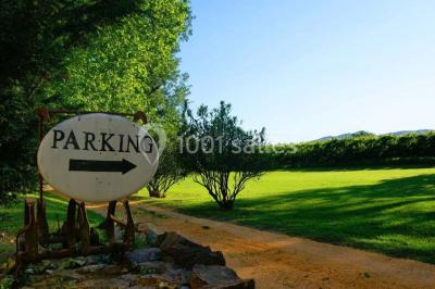 Un homme en costume soulève une femme en robe blanche dans un jardin au coucher du soleil.
