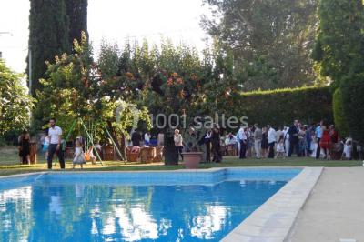 Un homme en costume soulève une femme en robe blanche dans un jardin au coucher du soleil.