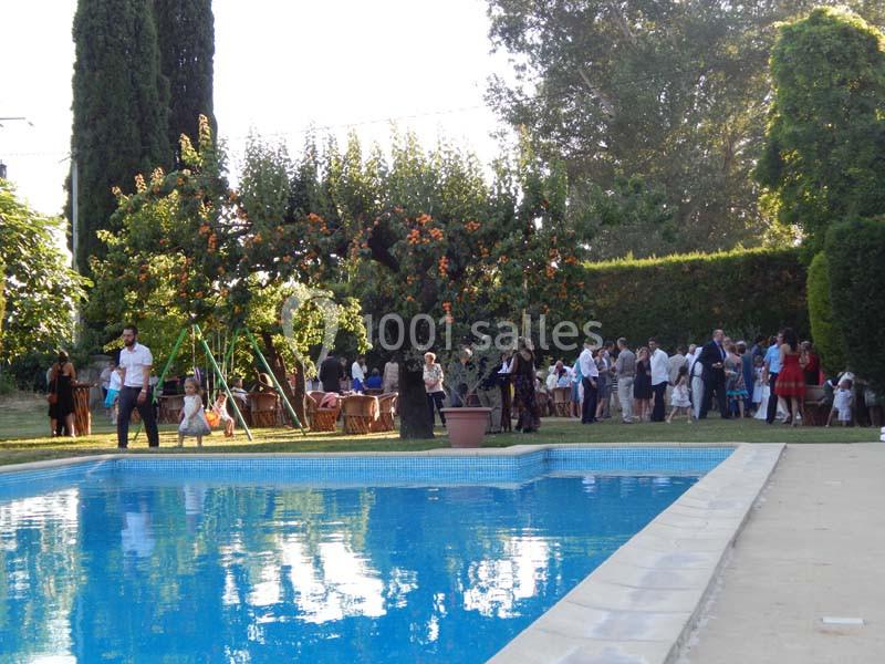 Groupe de personnes rassemblées dans un jardin près d'une piscine, entouré d'arbres et de végétation.