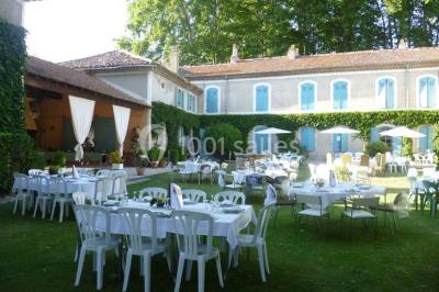 Un homme en costume soulève une femme en robe blanche dans un jardin au coucher du soleil.
