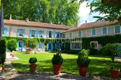 Un homme en costume soulève une femme en robe blanche dans un jardin au coucher du soleil.