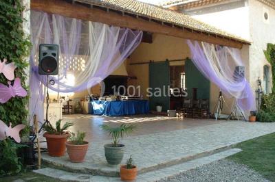 Un homme en costume soulève une femme en robe blanche dans un jardin au coucher du soleil.