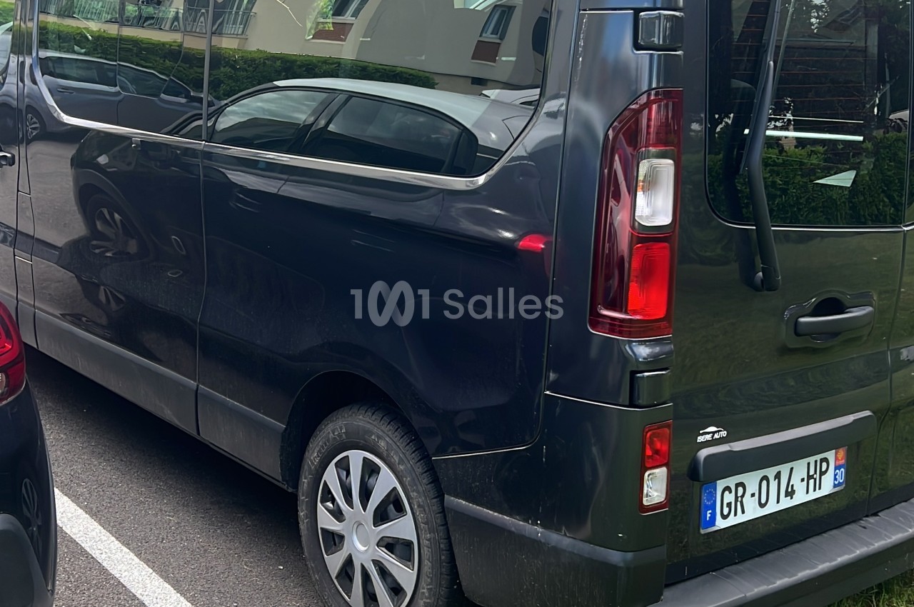 Véhicule utilitaire monospace noir garé de profil arrière sur un parking, vitres teintées et plaque d'immatriculation française visibles.