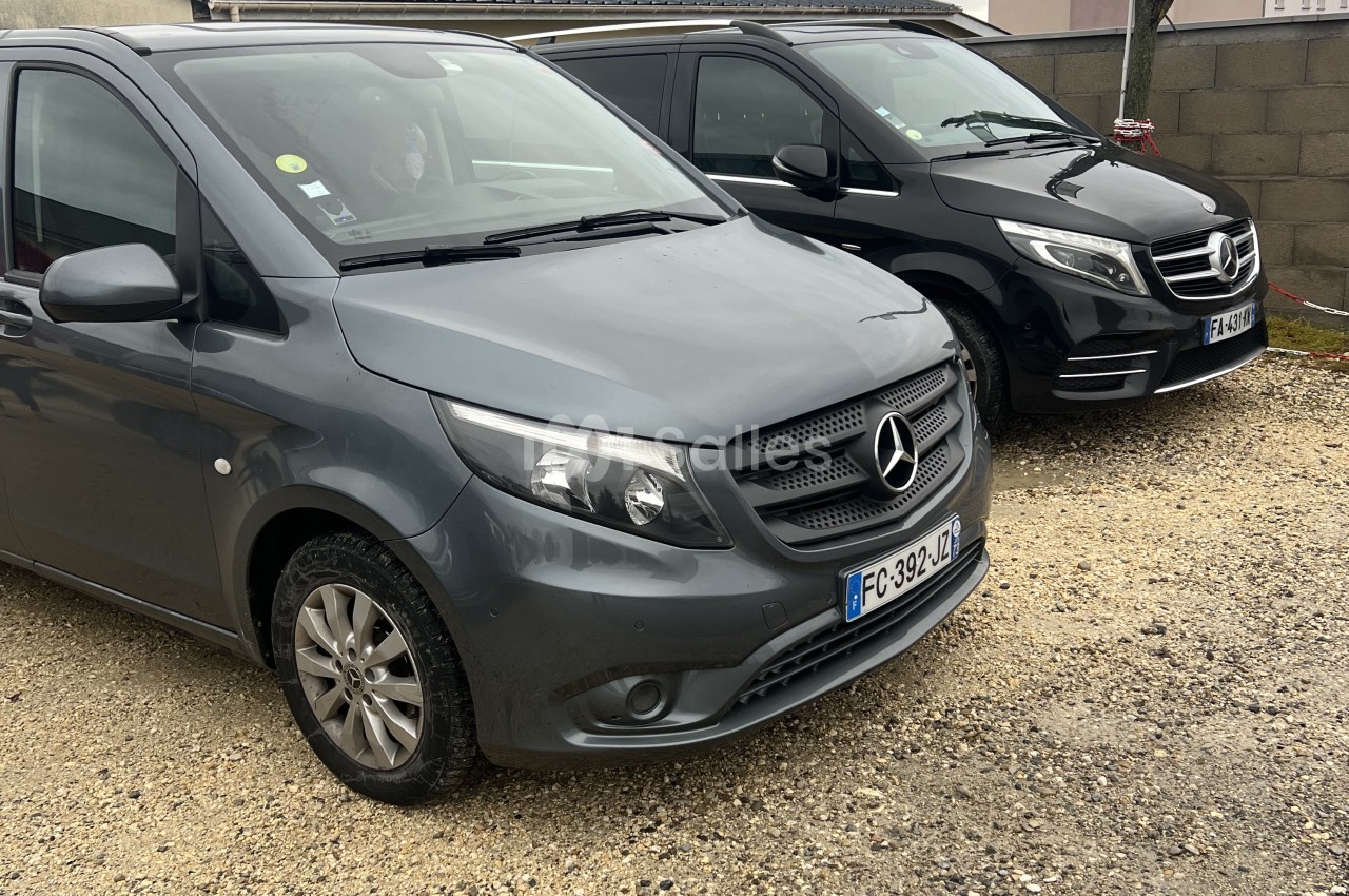 Deux minibus de tourisme Mercedes, l'un gris et l'autre noir, garés sur un sol de gravier.
