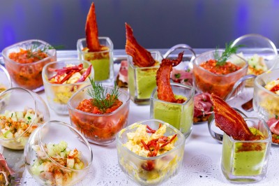 Salle lumineuse avec des tables en bois, des stands d'exposition et des personnes observant ou manipulant des objets.