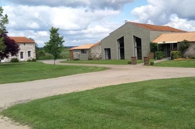Terrasse en bois avec garde-corps métallique, offrant une vue dégagée sur un paysage champêtre sous un ciel bleu.