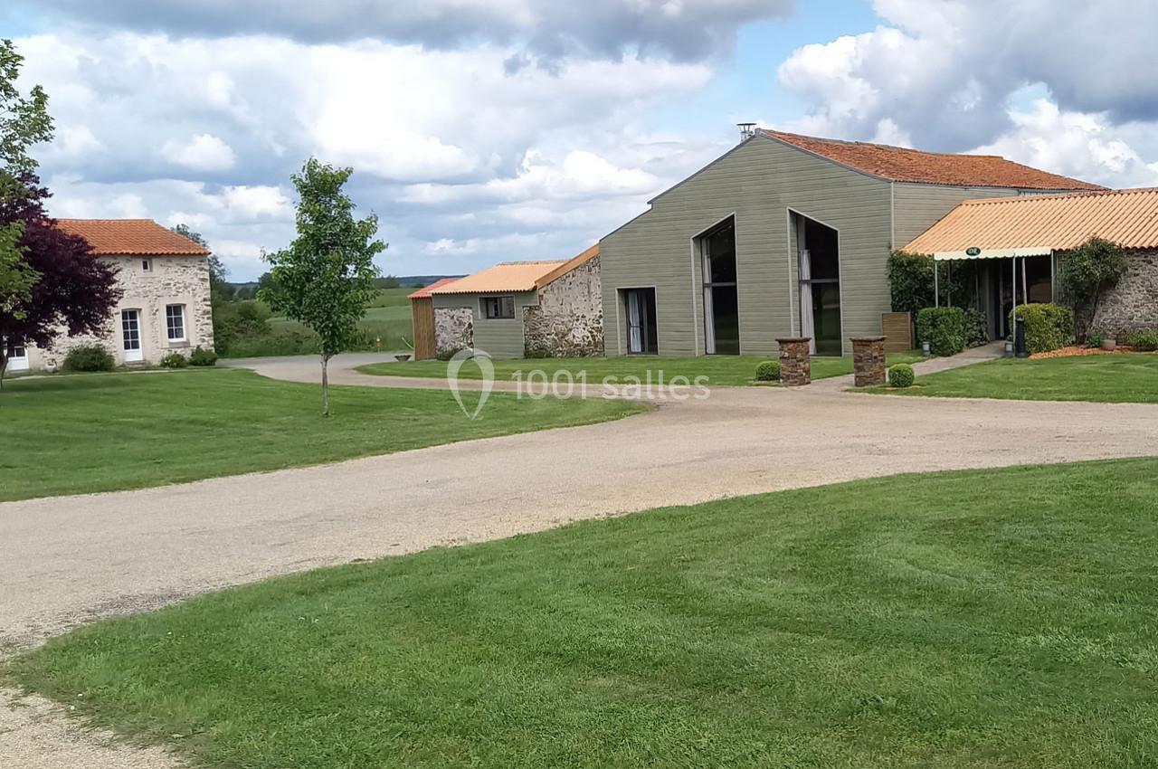 Bâtiments modernes et traditionnels entourés de pelouses et d'arbres sous un ciel partiellement nuageux.