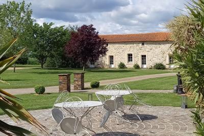 Terrasse en bois avec garde-corps métallique, offrant une vue dégagée sur un paysage champêtre sous un ciel bleu.