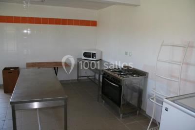 Terrasse en bois avec garde-corps métallique, offrant une vue dégagée sur un paysage champêtre sous un ciel bleu.
