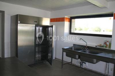 Terrasse en bois avec garde-corps métallique, offrant une vue dégagée sur un paysage champêtre sous un ciel bleu.