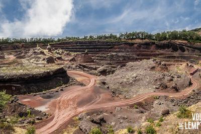 Vue d'une carrière avec des fleurs violettes au premier plan et une petite structure blanche en arrière-plan.