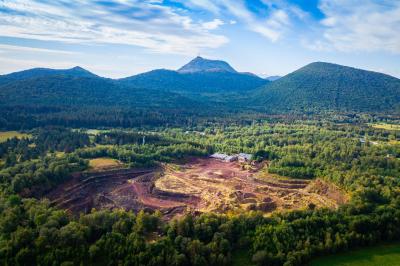 Vue d'une carrière avec des fleurs violettes au premier plan et une petite structure blanche en arrière-plan.