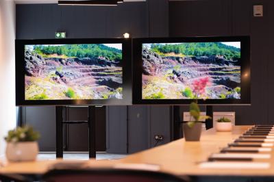 Chambre lumineuse avec lit double, mur décoré de papier peint à motifs végétaux et éclairage d'appoint.