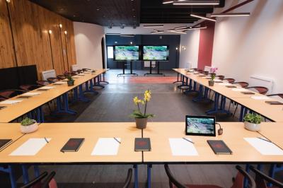 Chambre lumineuse avec lit double, mur décoré de papier peint à motifs végétaux et éclairage d'appoint.