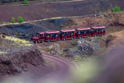 Paysage d'une ancienne carrière volcanique avec des formations rocheuses, entourée de végétation et sous un ciel bleu.