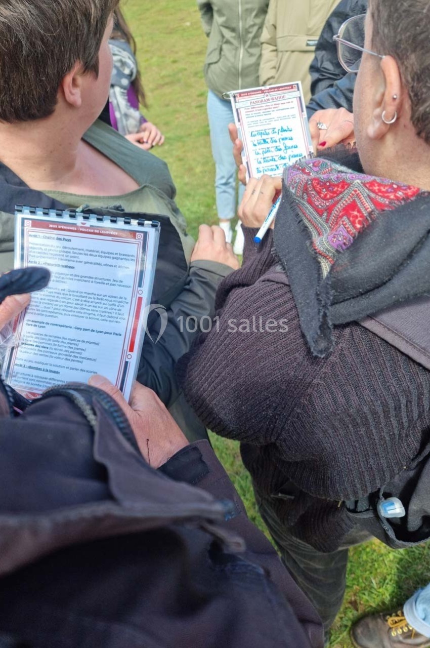 Des personnes en extérieur lisent des documents plastifiés, probablement lors d'une activité ou d'une discussion en groupe.