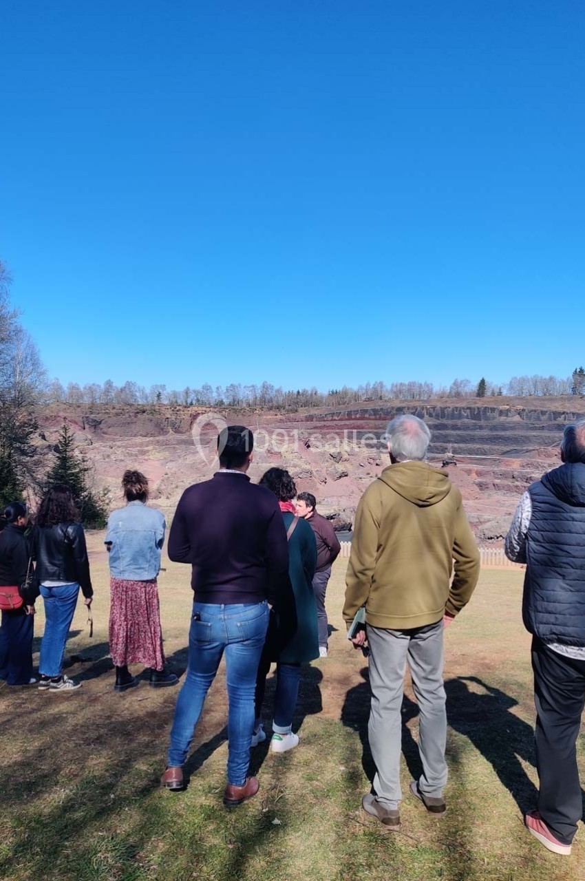 Un groupe de personnes observe un paysage de carrière sous un ciel bleu dégagé.
