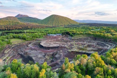 Paysage d'une ancienne carrière volcanique avec des formations rocheuses, entourée de végétation et sous un ciel bleu.